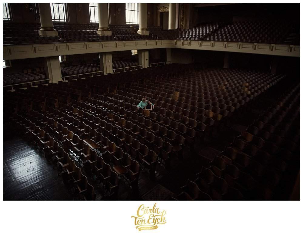 A couple sits in the middle of the theatre on the Yale campus during their engagement session in New Haven CT
