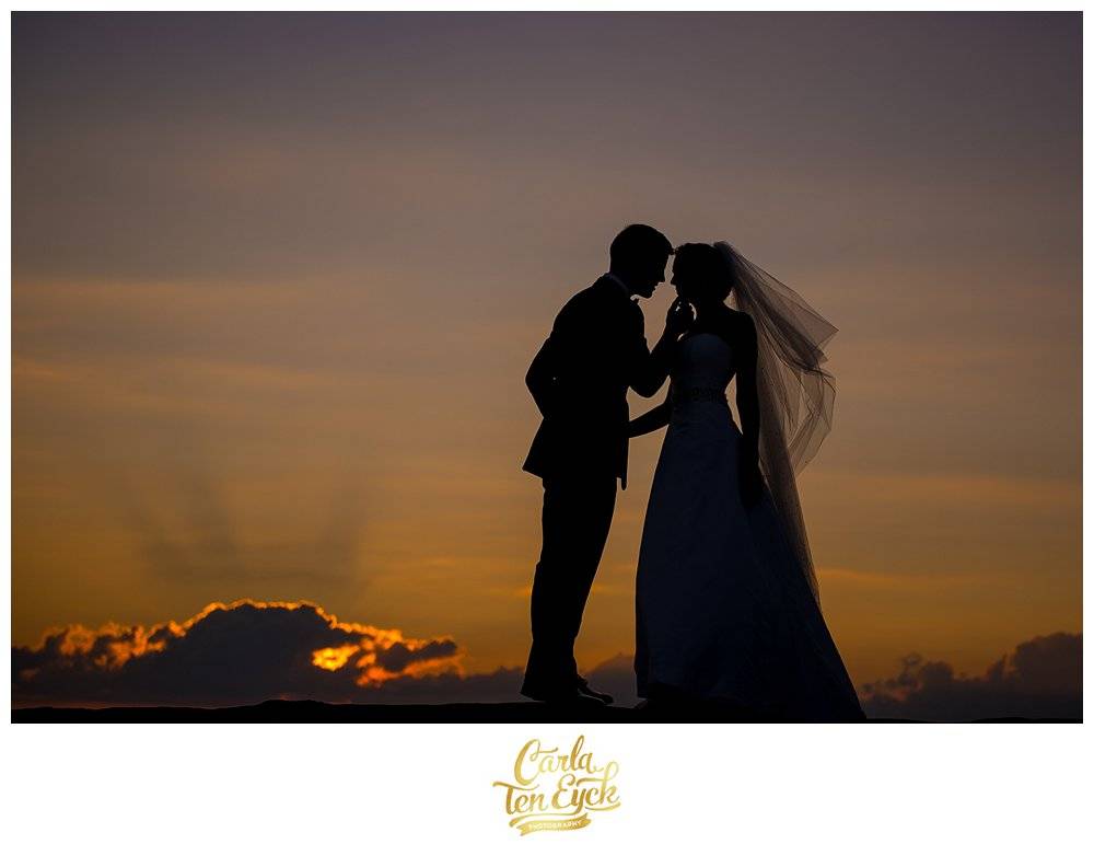 A bride and groom kiss during sunset at their wedding at the Branford House in Groton CT
