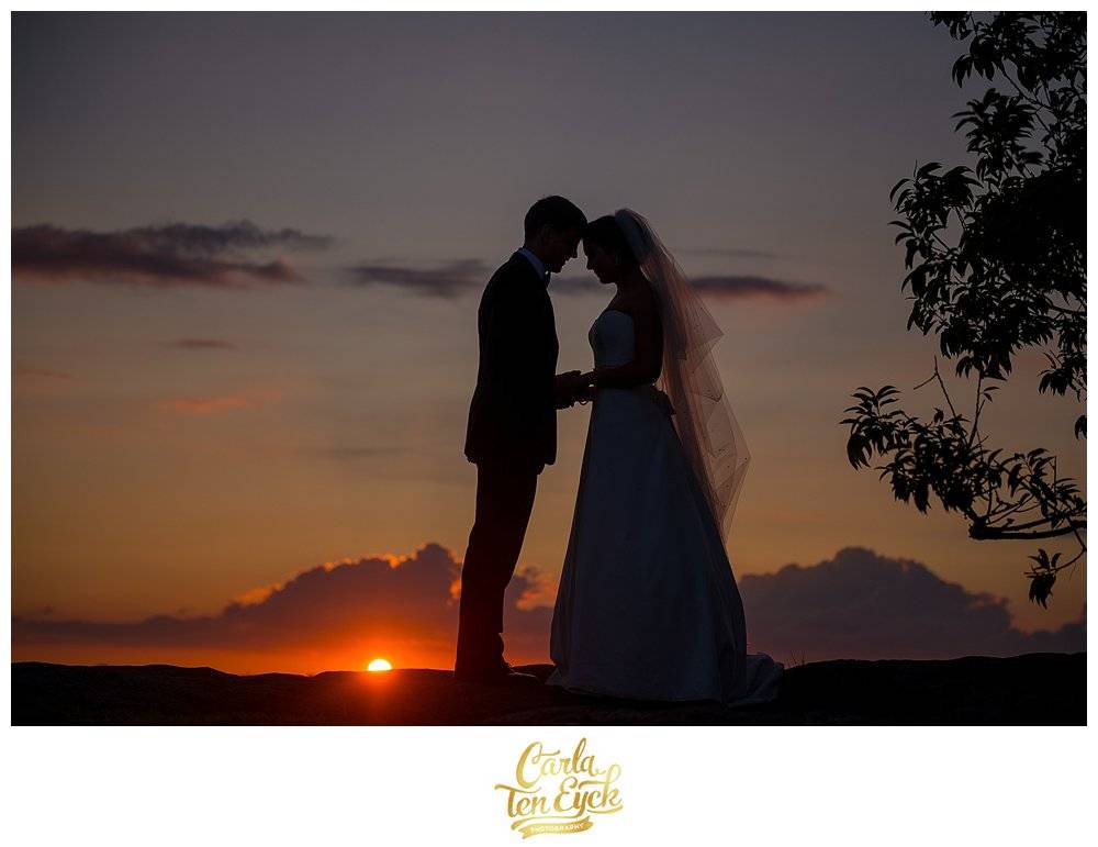 A bride and groom take a break during sunset at their wedding at the Branford House in Groton CT