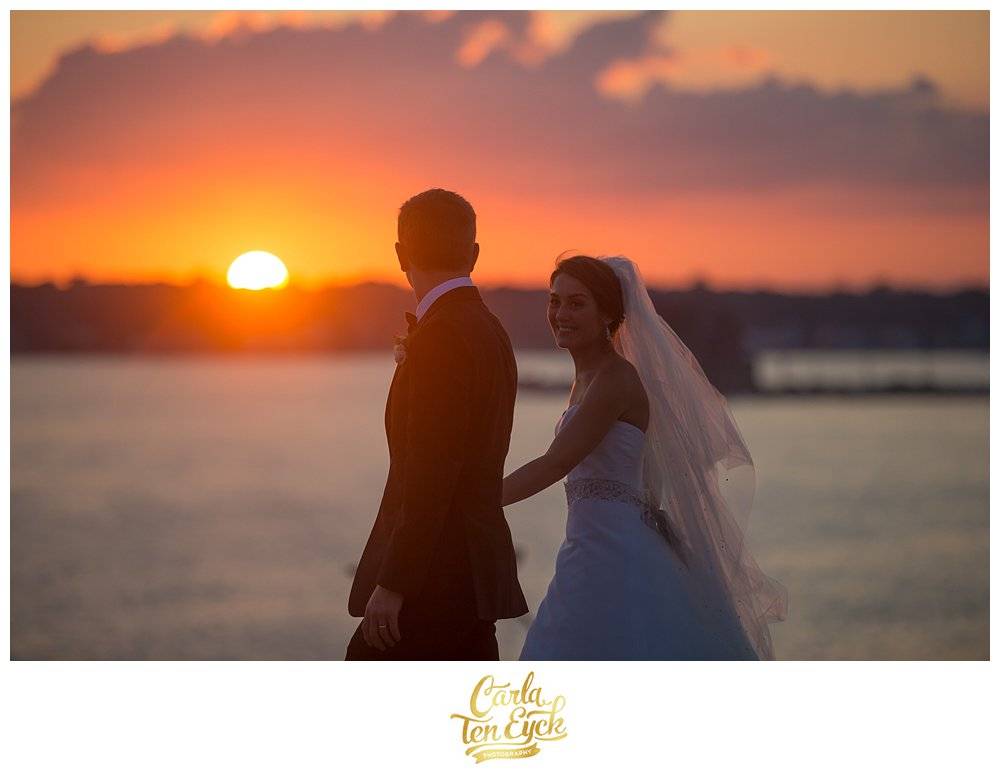 A bride looks at her husband during sunset at their wedding at the Branford House in Groton CT