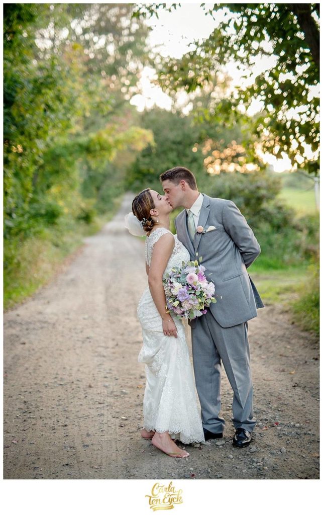 Bride and groom kiss on a dirt road at their Tyrone Farm wedding, Pomfret CT