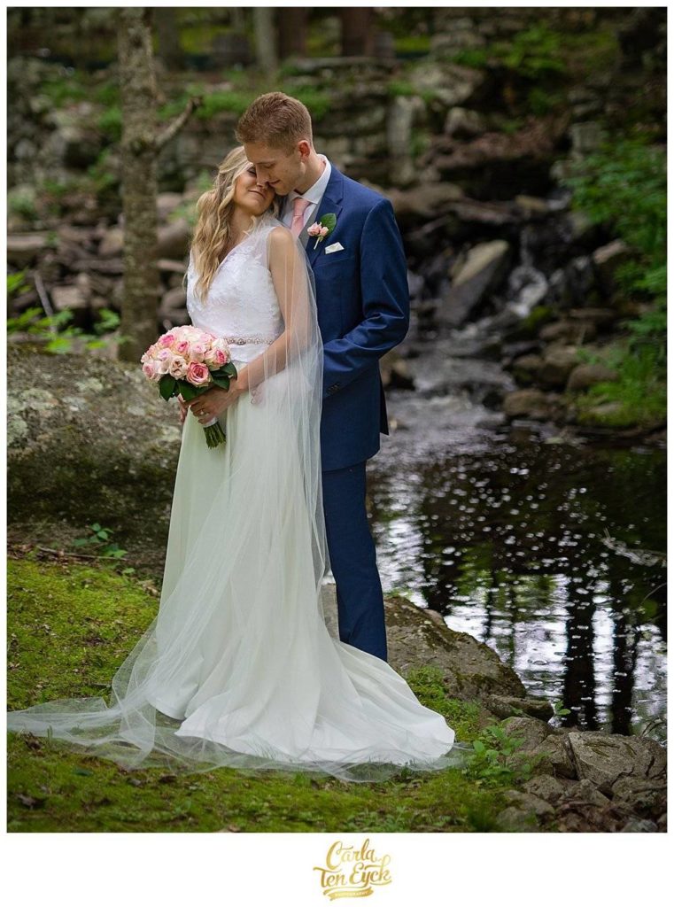 Bride and Groom snuggling on a mossy bank next to a waterfall at Wright's Mill Farm in Canterbury CT