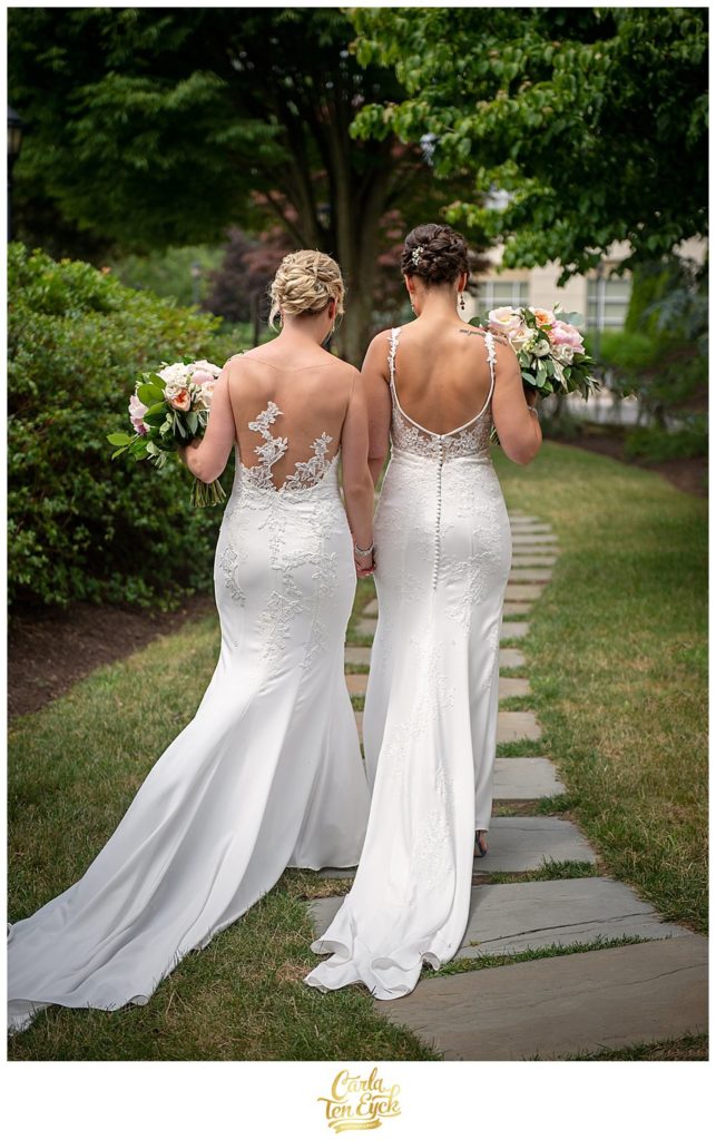 Two brides in Pronovias and Enzoani wedding gowns walk to their wedding at Jonathan Edwards Winery North Stonington CT