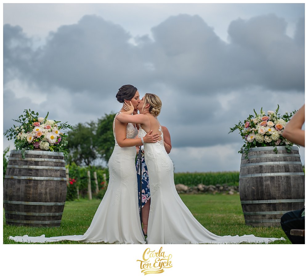 Two brides share their first kiss at their wedding ceremony at Jonathan Edwards Winery North Stonington CT