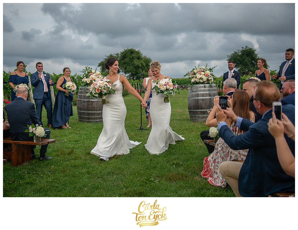 Two brides walk down the aisle after their wedding ceremony at Jonathan Edwards Winery North Stonington CT