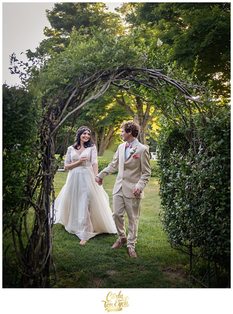 Bride and groom walk through arch on Smith Farm Gardens in CT on their wedding day