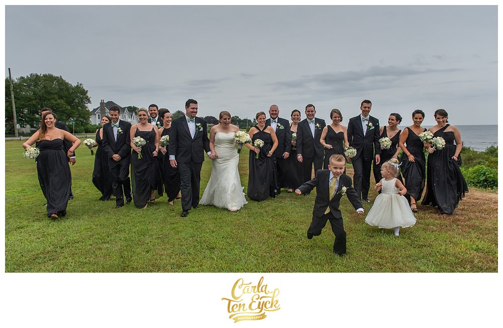Wedding party walking in the rain by the beach during their tented CT wedding