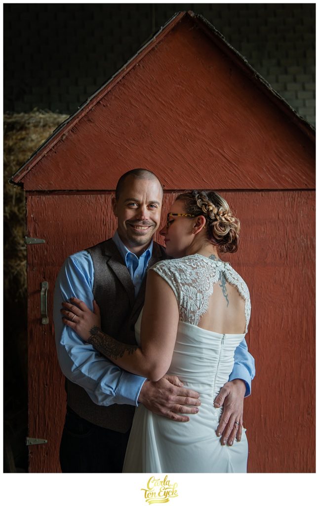 Groom holds his bride by a barn at their wedding at Cold Spring Farm in Colchester CT