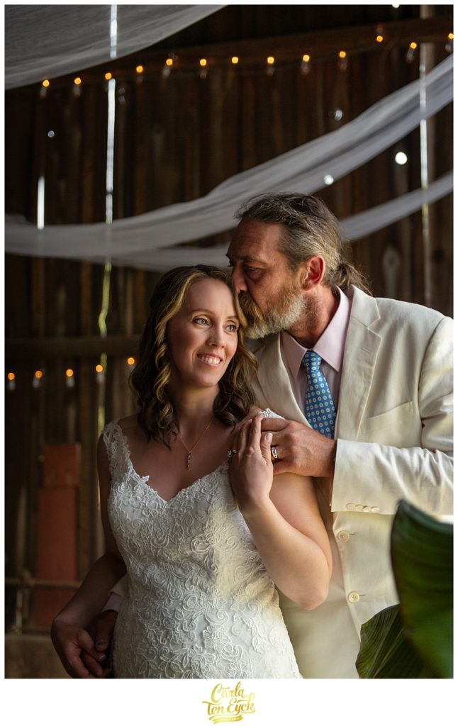 Groom kisses his bride in the tobacco barn at their backyard CT wedding