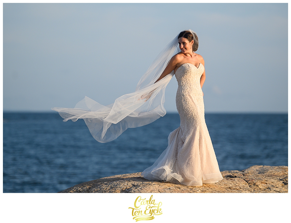 Bride lets her veil blow in the wind on the rocks at her wedding at The Owenego Inn in Branford CT