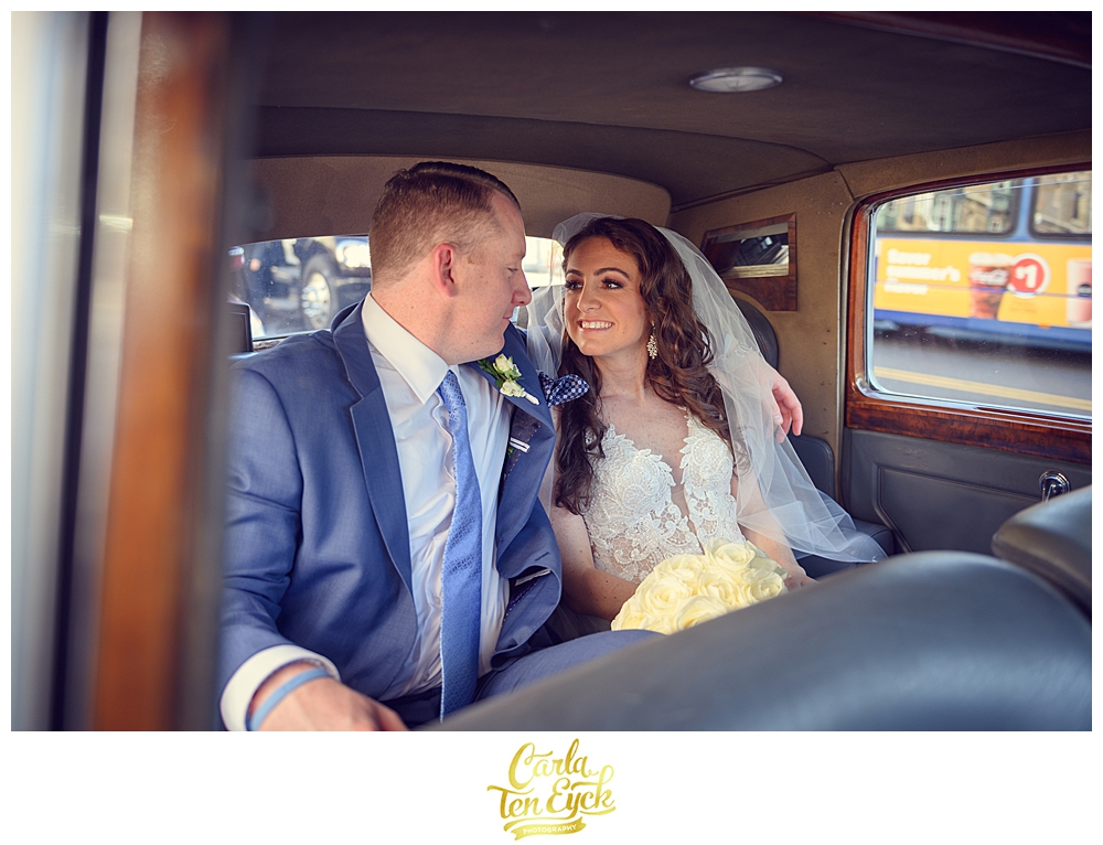 Bride and groom smile at one another in their classic car at Aria in Prospect CT