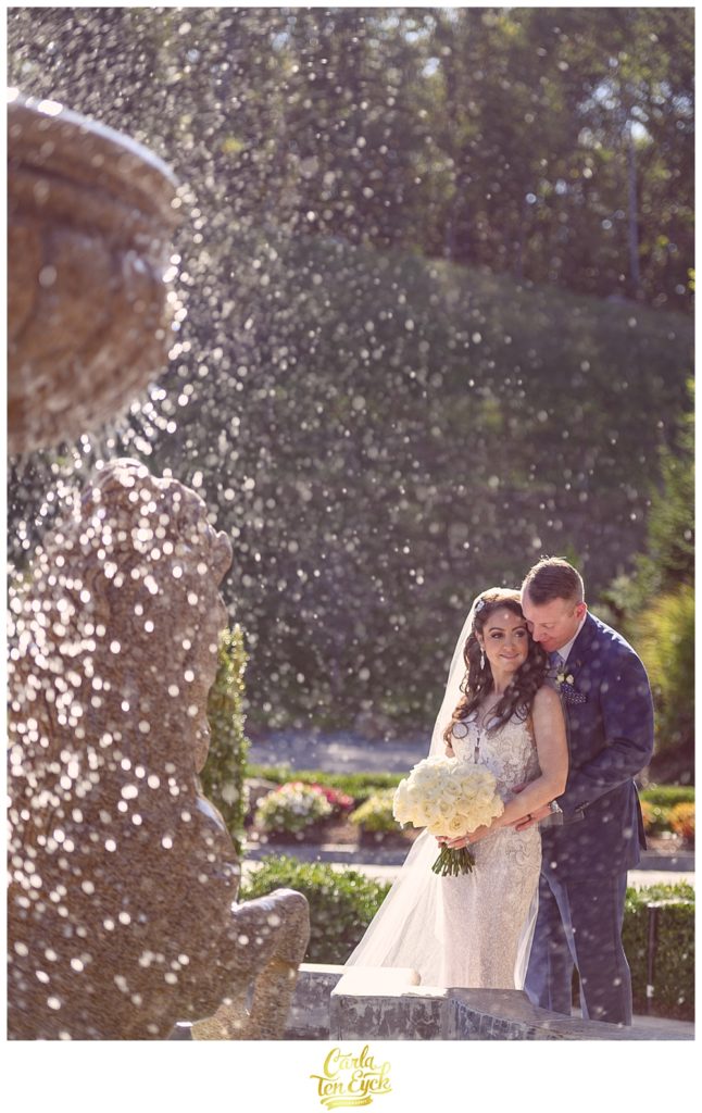 A bride and groom snuggle near the fountain at Aria in Prospect CT on their wedding day