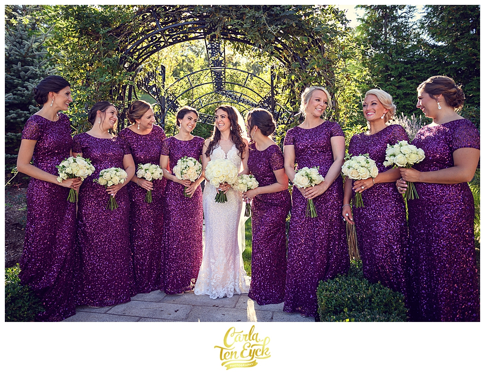 A bridal party in purple sequin bridesmaids dresses laughs at a wedding at Aria in Prospect CT