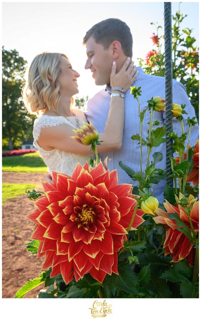 A couple embraces by a giant dahlia on their CT engagement session in Elizabeth Park in Hartford CT