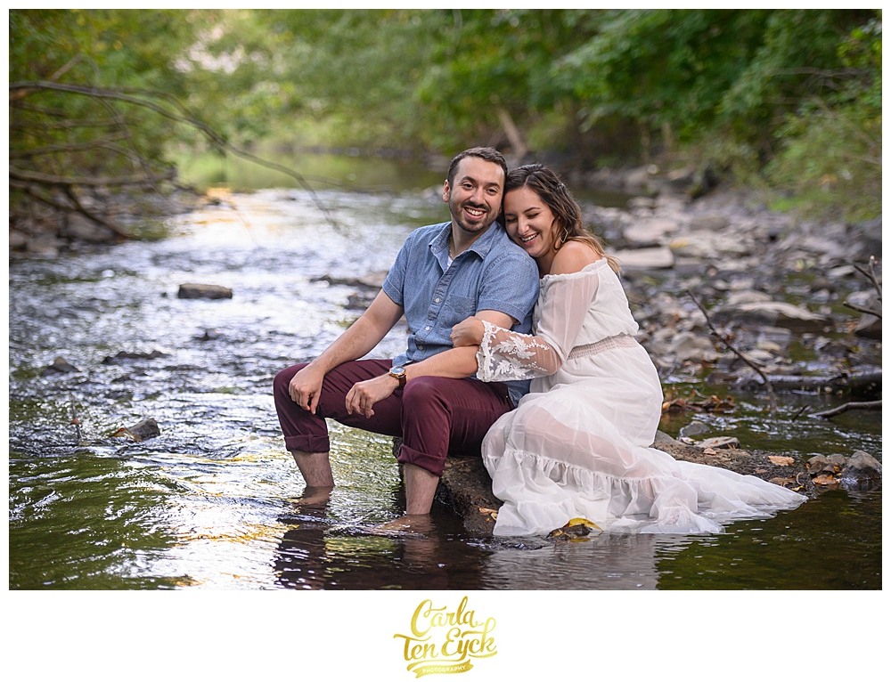 A couple laughs during their engagement session in the Hog River in Hartford's Historic West End