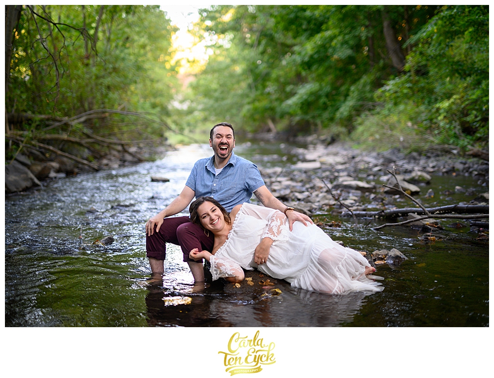 A couple laughs in the Hog River during their engagement session in Hartford CT