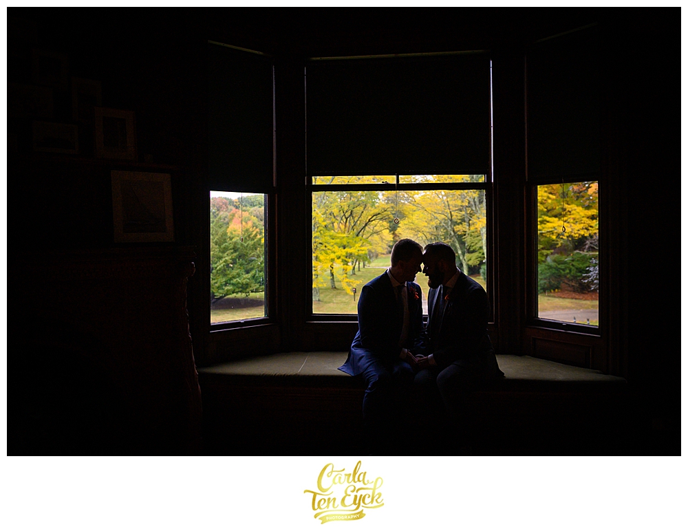 Tow grooms snuggle in a window at their wedding at the Eustis Estate in Milton MA