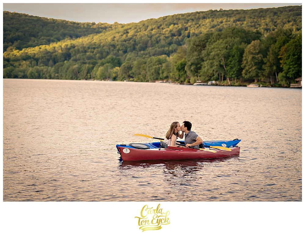 A couple kisses while kayaking on Lake Waramaug CT during their engagement session