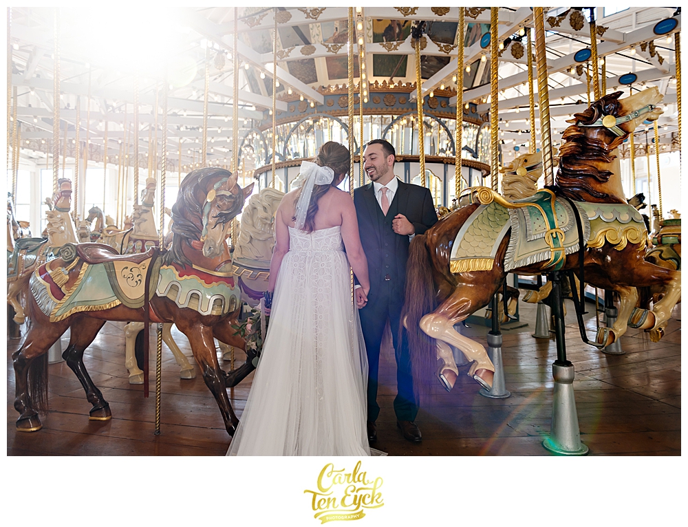 A bride and groom pose for photos on the carousel at their wedding at Lighthouse Point Park in New Haven CT