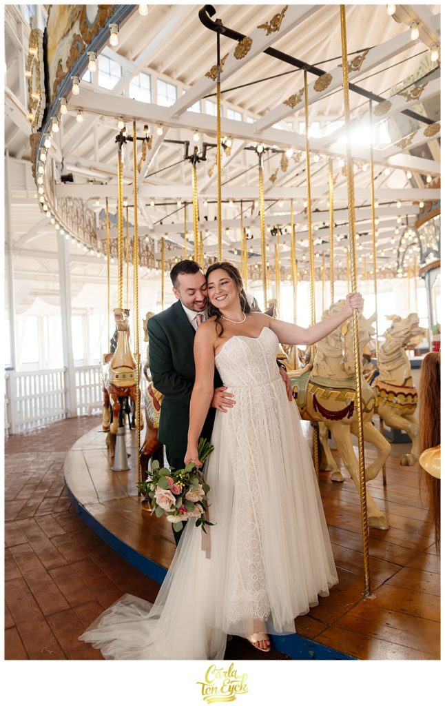 A bride and groom pose on the carousel for photos at their wedding at Lighthouse Point Park in New Haven CT 
