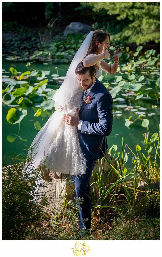 A groom picks up his bride by the lily pond at their wedding at Chatfield Hollow Inn in Killingworth CT