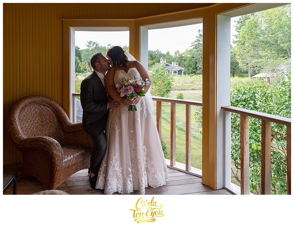 A bride and groom kiss on the balcony of the Charter Oak Suite at their intimate Winvian Wedding in Morris CT