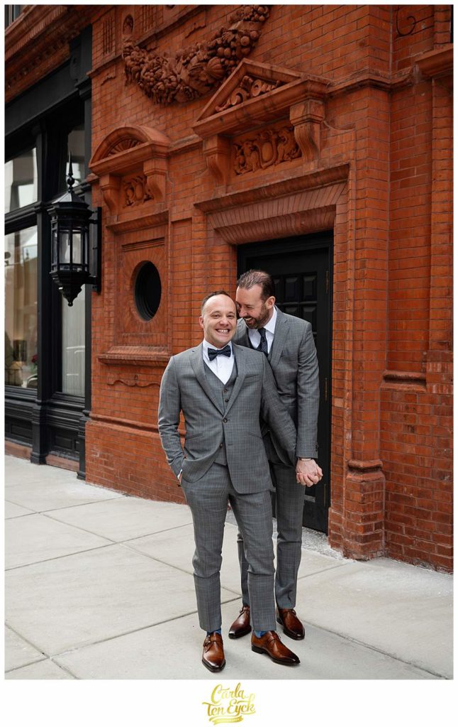 Two grooms pose for wedding photos outside of The Goodwin Hotel in Hartford CT