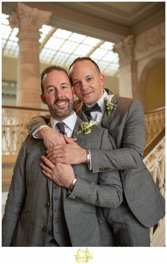 Two grooms snuggle for photos during their elopement in Hartford City Hall