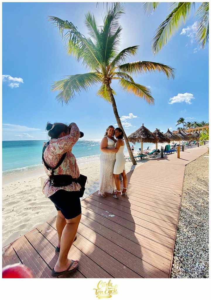 A photographer works on the beach with two brides at their Aruba Wedding at the Tamarijn Resort