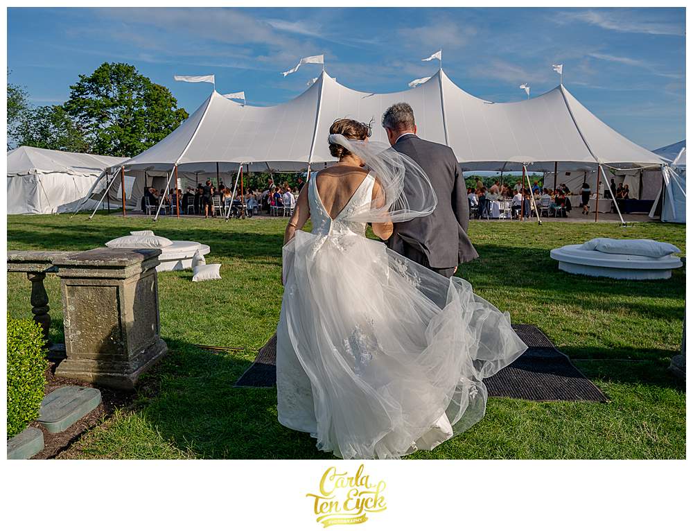 A couple walks toward the reception tent during their Fairfield University wedding in Fairfield CT