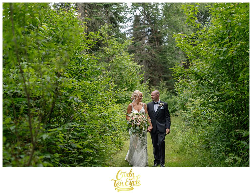 A couple walks in the woods for photos during their New Hampshire wedding.