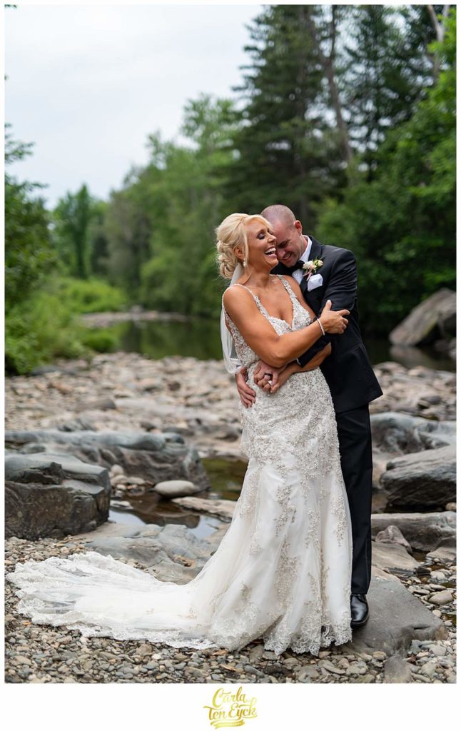 A couple laughs in a stream during their New Hampshire wedding
