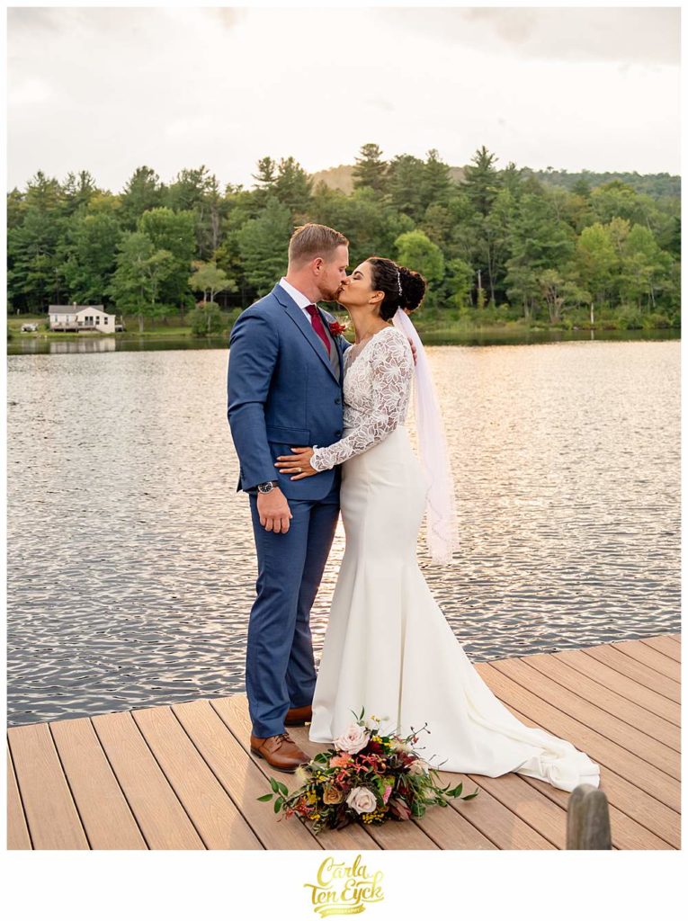 A couple kisses on the swim platform at their summer camp wedding at Camp Lenox in Otis MA