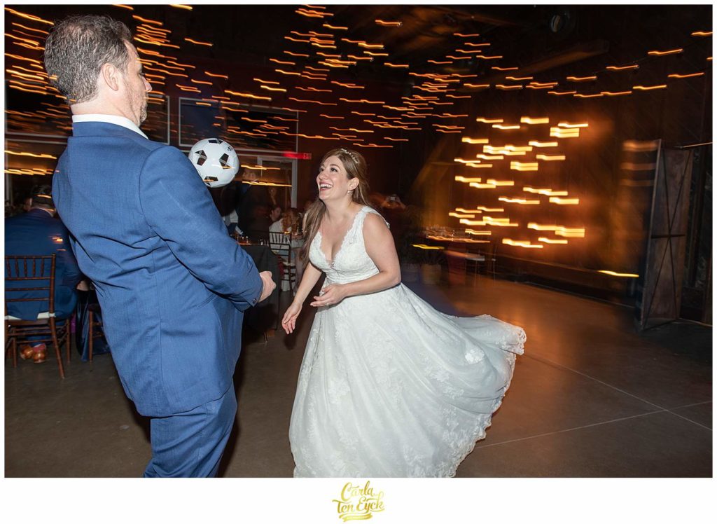 A bride and groom play soccer during their autumn Saltwater Farm vineyard wedding in Stonington CT