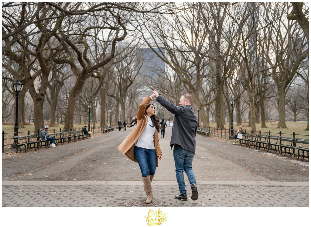 A couple dances along the iconic Mall in Central Park during their winter engagement session 