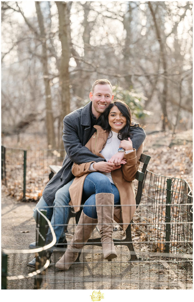 A couple cuddles in The Ramble in Central Park for their winter engagement session
