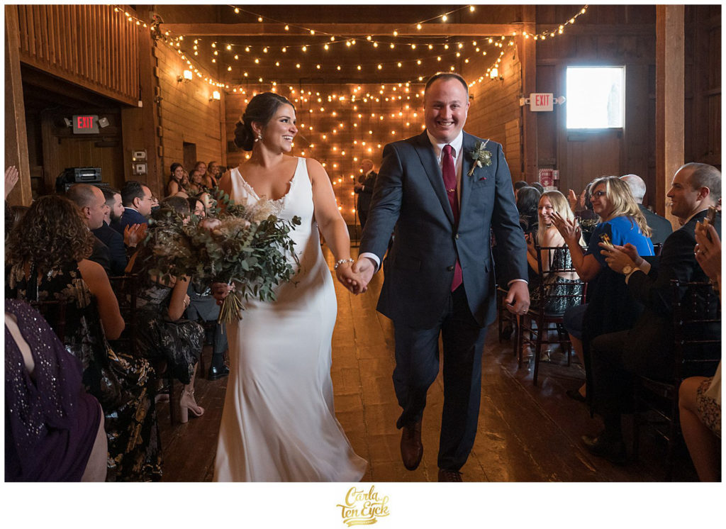 A bride and groom walk down the aisle at their wedding at The Barns at Wesleyan Hills in Middletown CT