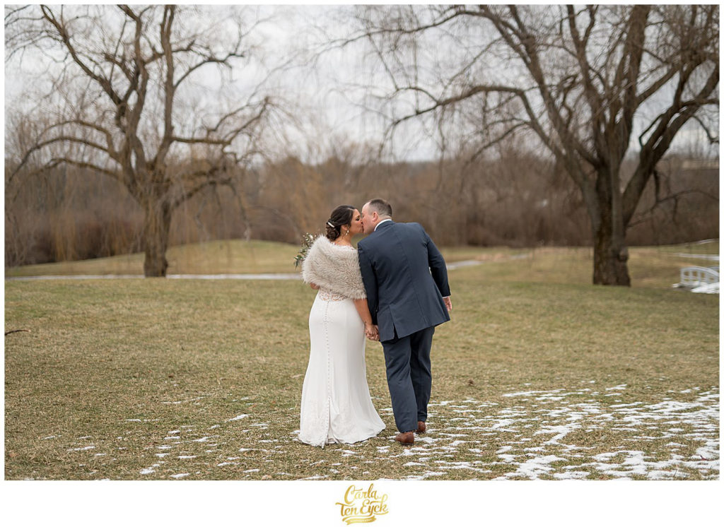 A bride and groom kiss in the winter at their wedding at The Barns at Wesleyan Hills in Middletown CT