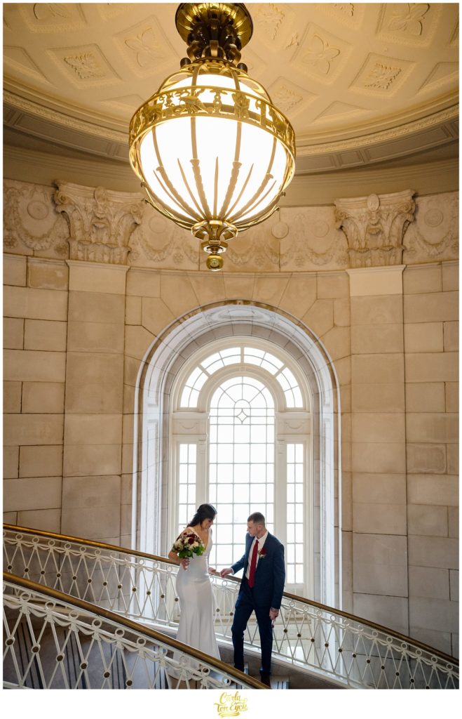 A bride and groom pose for wedding photos on the grand staircase at their Hartford City Hall Spring elopement, in Hartford CT