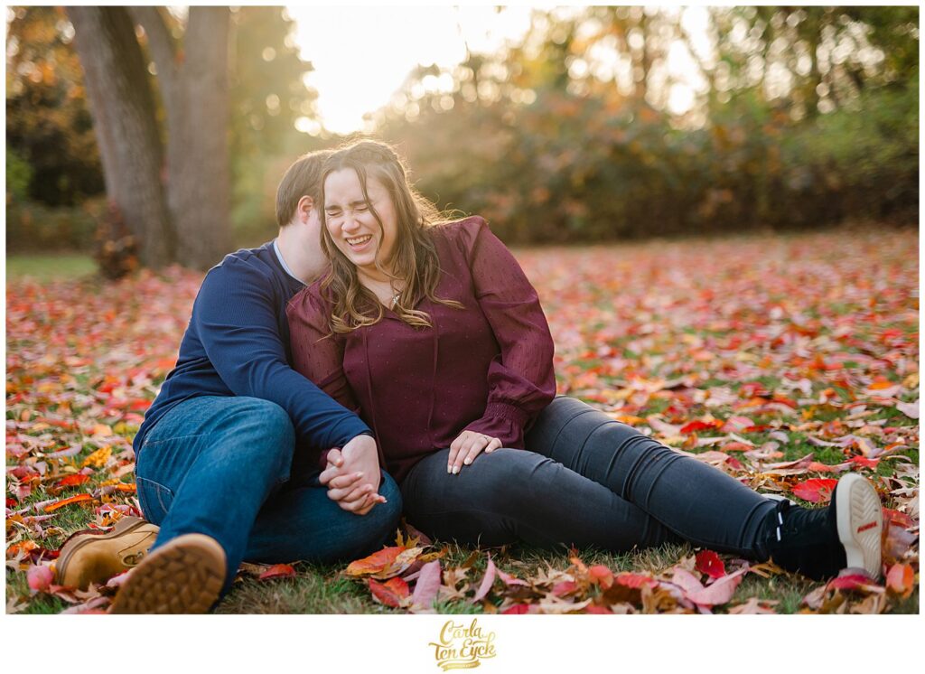 A couple laughs in the leaves during their CT fall engagement session in Elizabeth Park, Hartford CT
