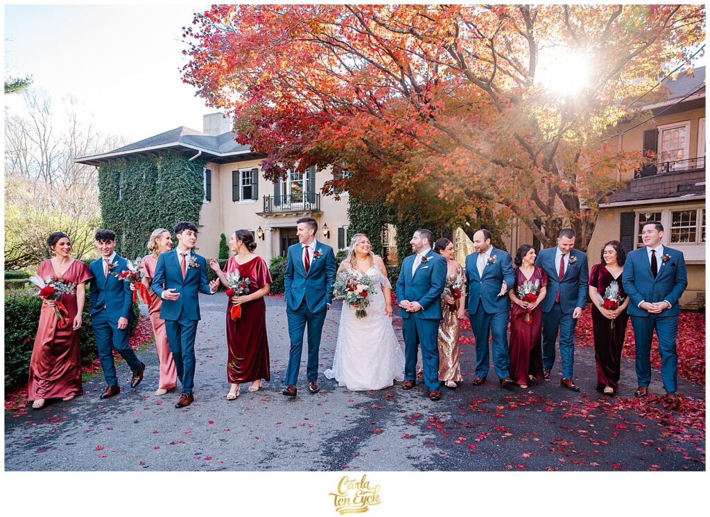 A wedding party walks and laughs during photos at an  autumn lord Thompson Manor wedding in Thompson CT
