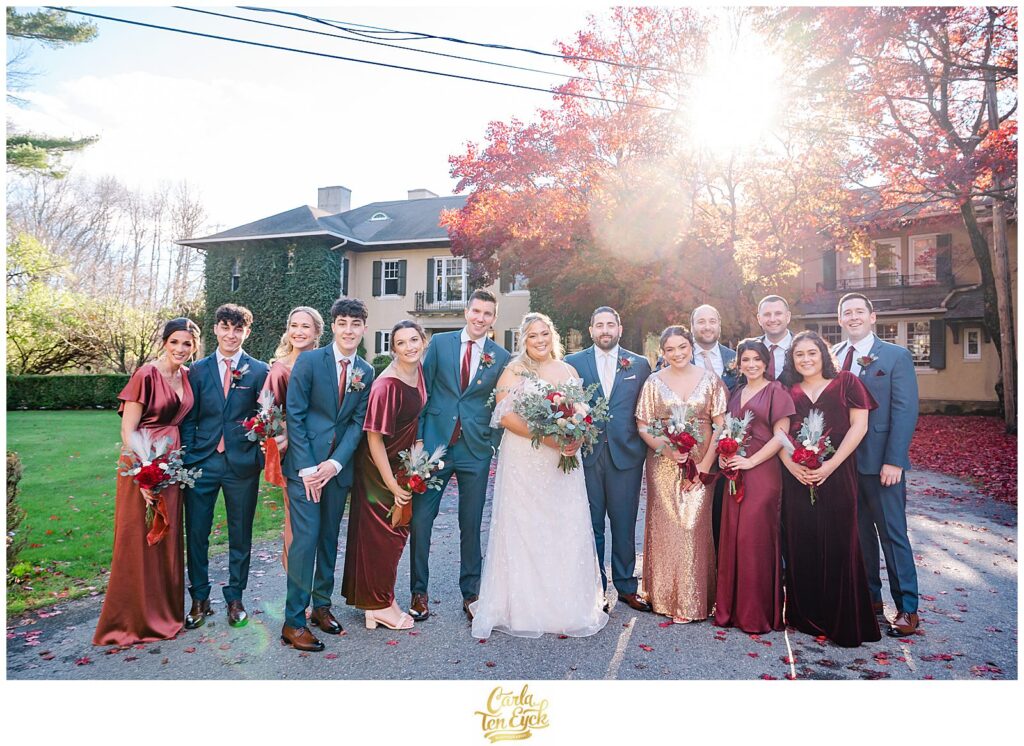 A wedding party basks in the late afternoon sun at an  autumn lord Thompson Manor wedding in Thompson CT
