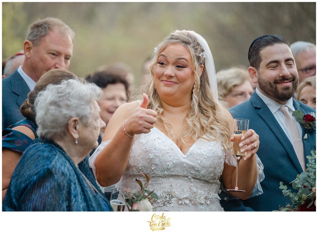 A bride gives a thumbs up at her  autumn lord Thompson Manor wedding in Thompson CT