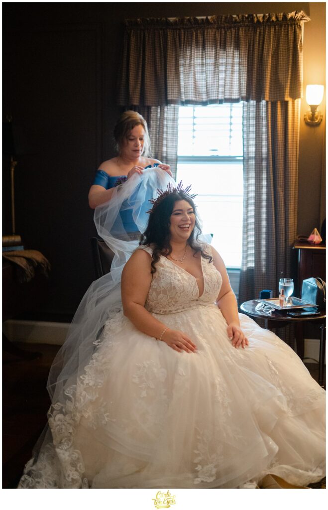 A Mom puts the veil on her daughter before their colorful wedding at Lord Thompson Manor in Thompson CT