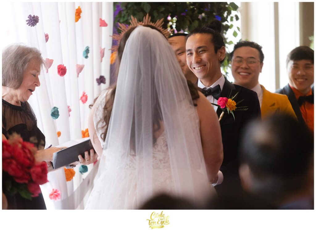 A groom smiles at his bride at their colorful wedding at Lord Thompson Manor in Thompson CT