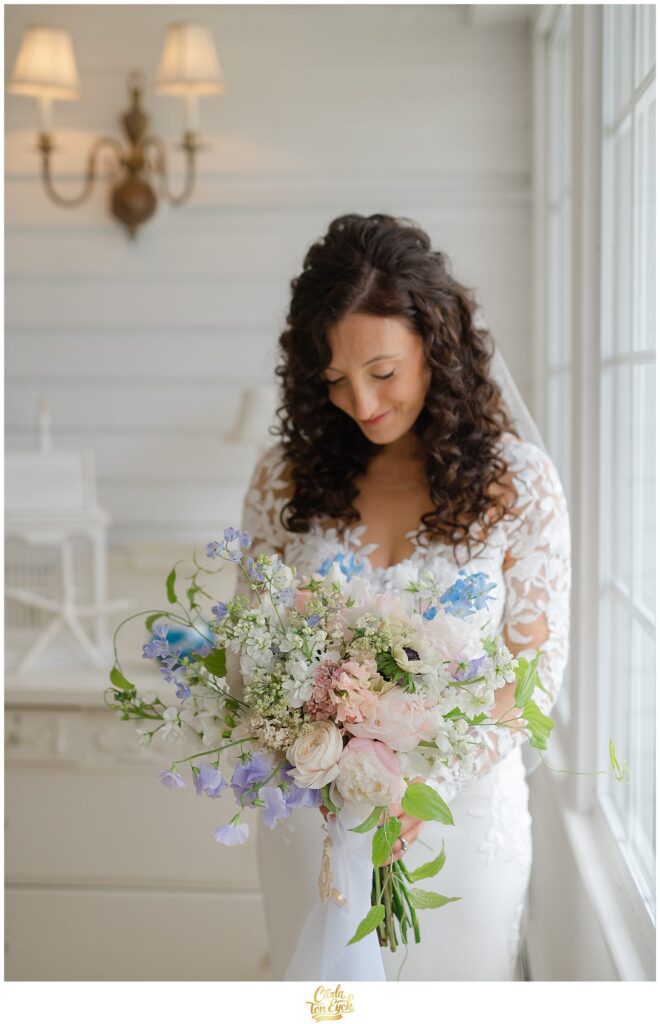 A bride looks at her gorgeous bouquet at her romantic wedding at Lord Thompson Manor in Thompson CT