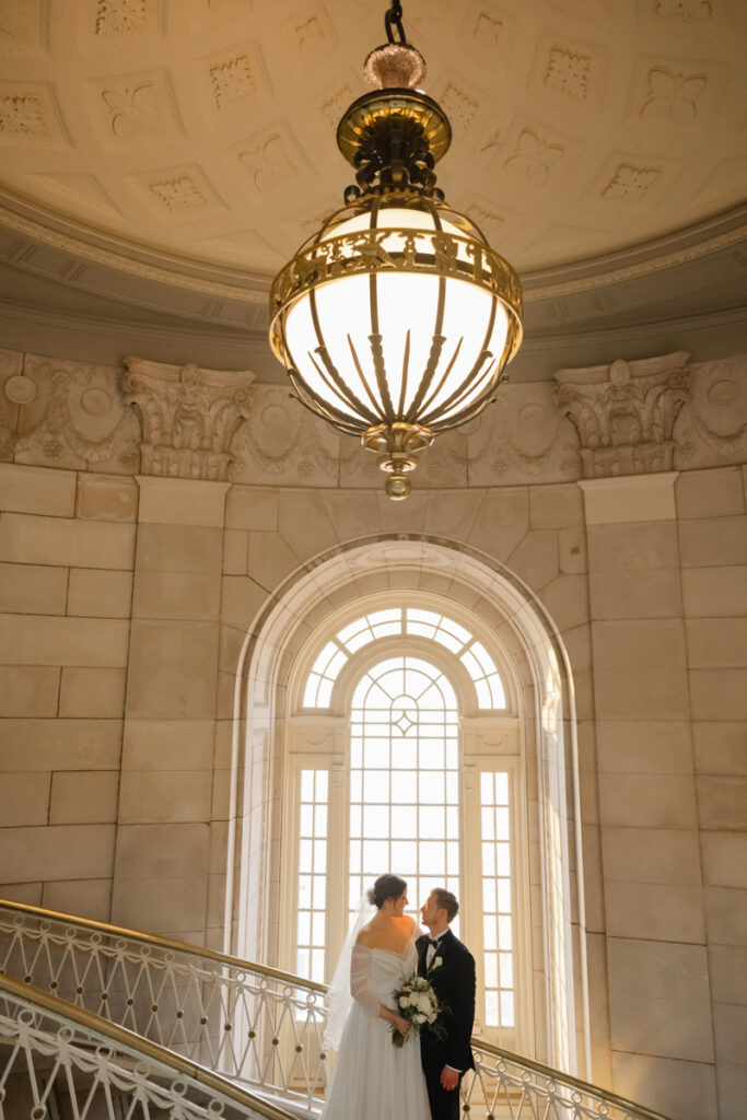 A couple soaks up the sunlight on the iconic staircase of Hartford City Hall after their elopement in Hartford CT.