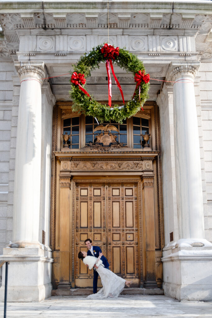 A groom dips his bride in front of the iconic gold doors after their elopement at Hartford City Hall in Hartford CT.