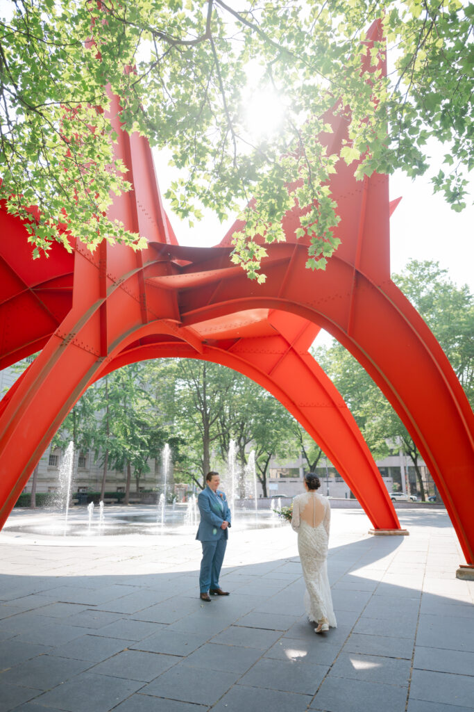 Two brides do their first look under Calder's Stegosaurus sculpture before their Hartford City Hall elopement