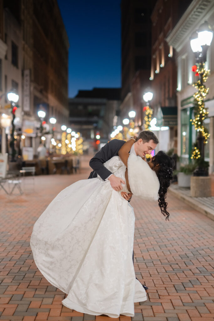 A couple dips and dances in their wedding clothes on Pratt Street in Hartford after their Hartford City Hall elopement
